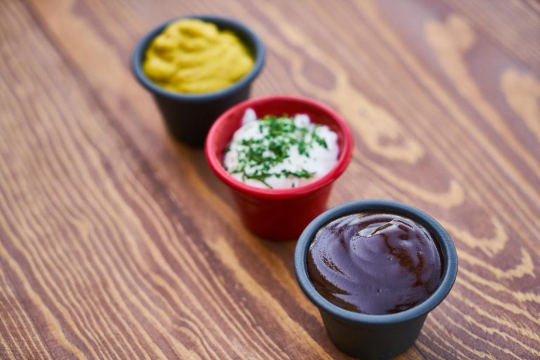 three assorted color of cream in containers on brown wooden slab