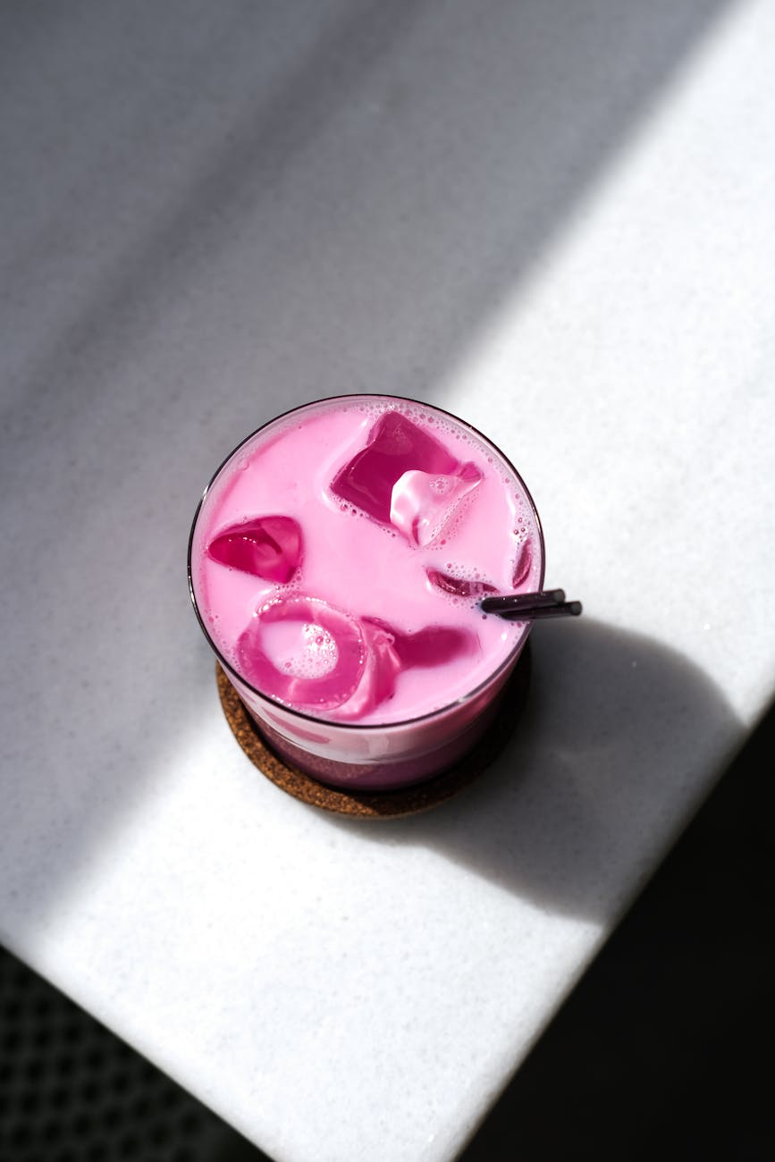 vibrant pink drink with ice on marble surface